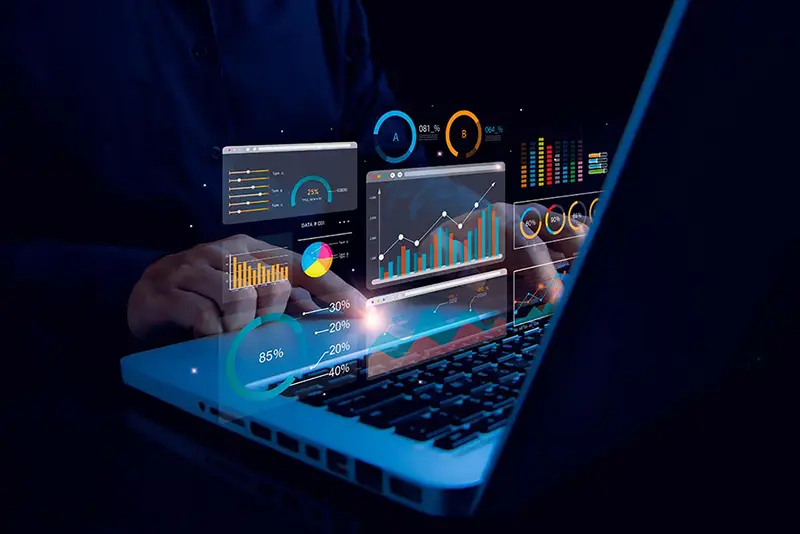 Person typing on a laptop with glowing screens displaying analytics charts and graphs for SEO Reporting Analytics Services.